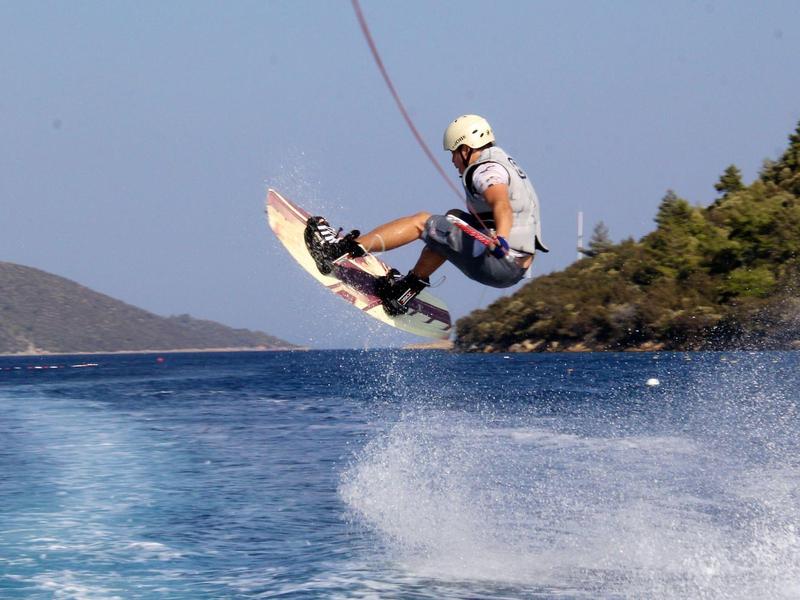 Man performing wakeboard jump over blue water with islands in the background
