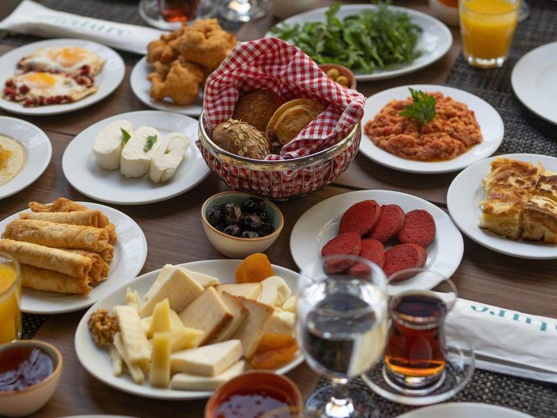 Table with a diverse breakfast spread including fresh fruit, pastries, cheese, and drinks.