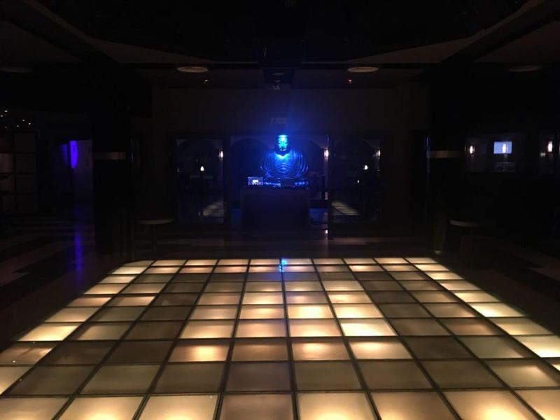 Empty illuminated dance floor in dark hotel bar with blue light source in background