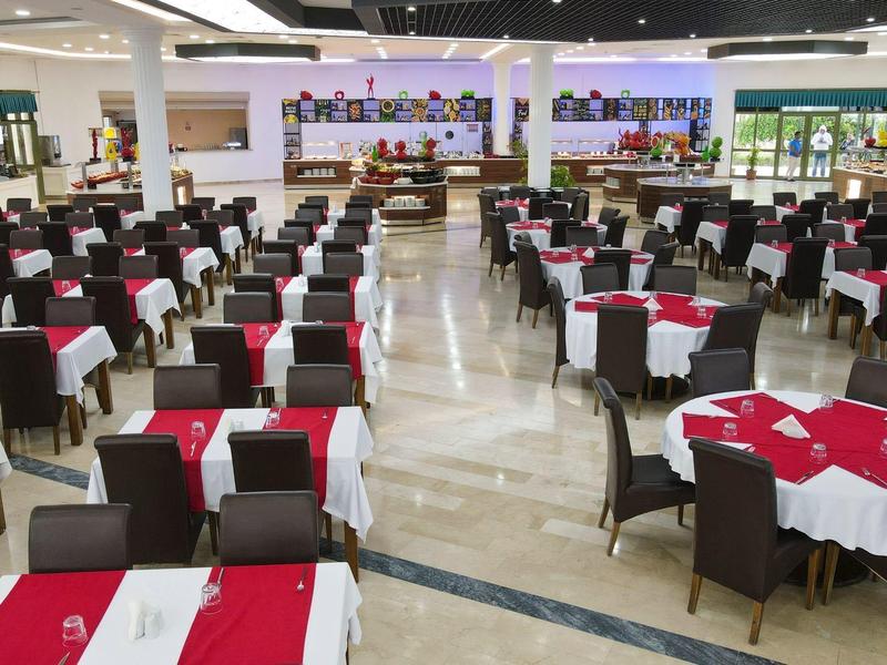 Großer, heller Saal mit vielen braunen Stühlen und Tischen, weiß-rote Tischdecken, Marmorboden.