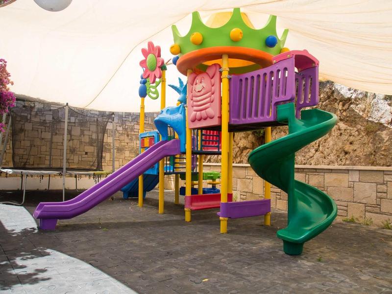 Area giochi colorata all'aperto per bambini con scivolo e struttura per arrampicata.