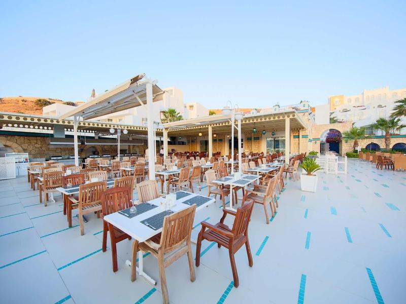 Grande terrazza dell'hotel con tavoli e sedie sotto un cielo limpido.