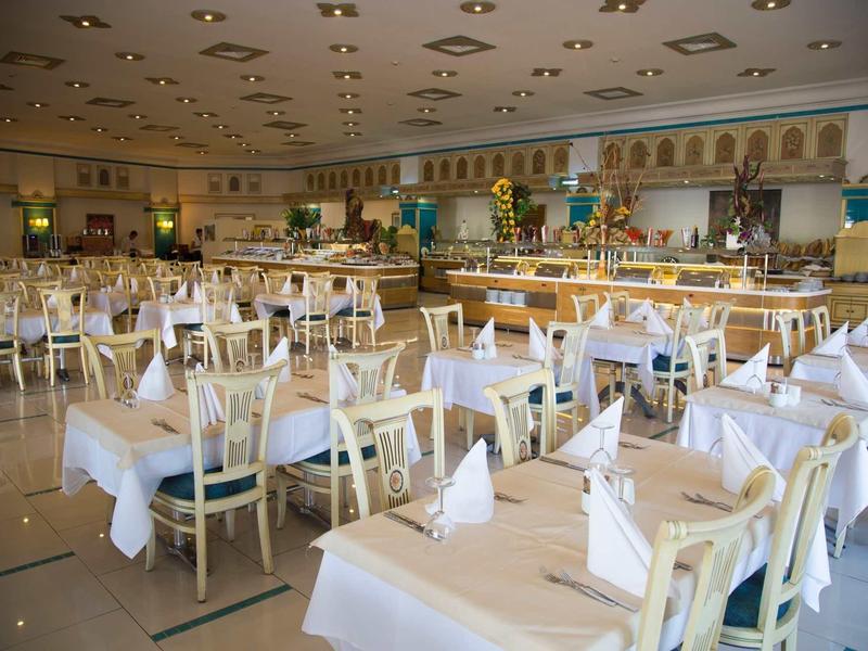 Grande sala da banchetto con tavoli apparecchiati bianchi e sedie di legno in un hotel.