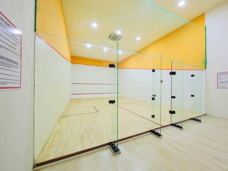 Campo da squash moderno con pareti in vetro e pavimento in legno chiaro in una struttura sportiva.