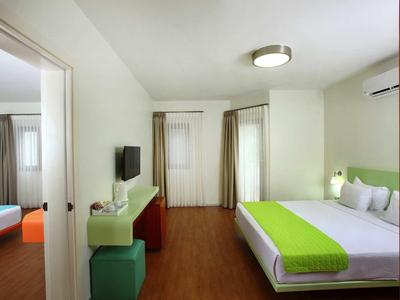 Modern hotel room with double bed, green accents, TV, and wooden flooring.