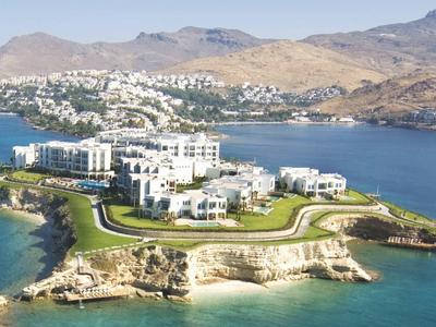 Luxe wooncomplex op een schiereiland met zeezicht en bergen op de achtergrond.