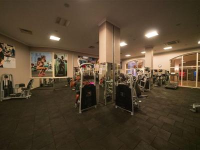 Ein gut ausgestatteter Fitnessraum mit verschiedenen Geräten und großen Fenstern.