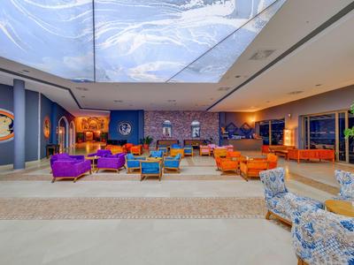 Großer Hotel-Lobbybereich mit bunten Sesseln und Sofas unter einer hellen Decke.