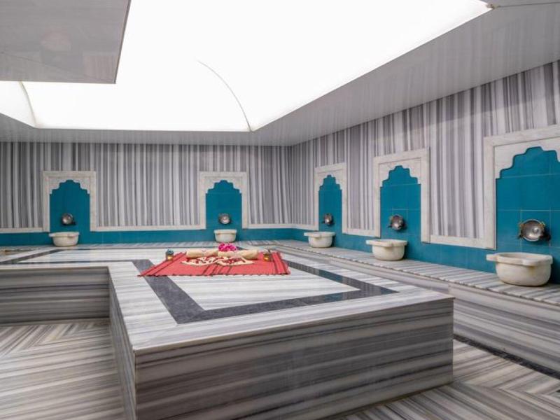 Modern gestaltetes Hamam mit weiß-grauen Marmorflächen und blau-weißen Wandnischen.