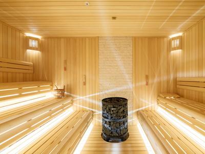 Helle, moderne Sauna mit Holzverkleidung, Saunasteinen und gemütlicher Beleuchtung.
