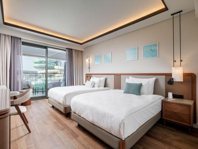 Modernes Hotelzimmer mit zwei Betten, Holzfußboden und Balkon mit Aussicht.