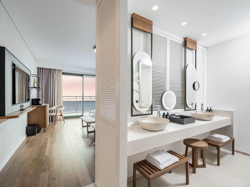 Nowoczesna łazienka z dwoma umywalkami i osobnym pokojem dziennym z widokiem na morze.