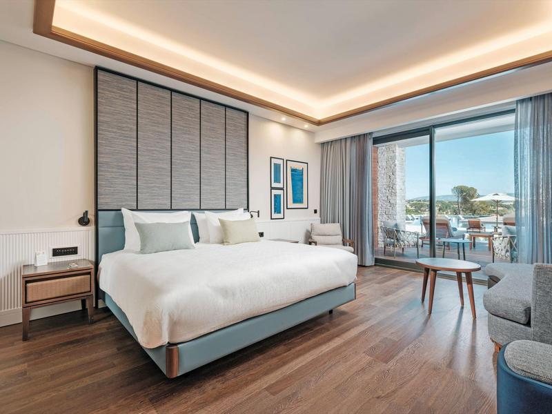 Nowoczesny pokój hotelowy z dużym łóżkiem, miejscem do siedzenia i balkonem z widokiem na morze.