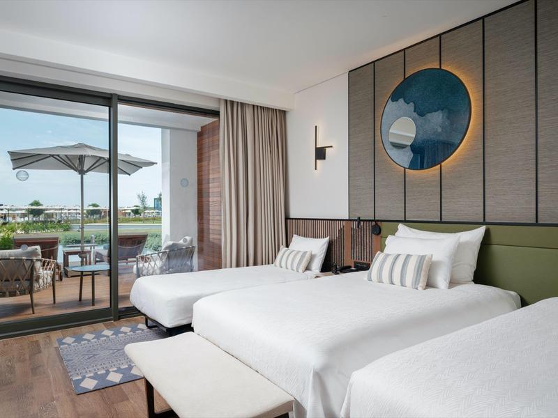 Nowoczesny pokój hotelowy z dwoma łóżkami i dostępem do tarasu z widokiem na ogród.