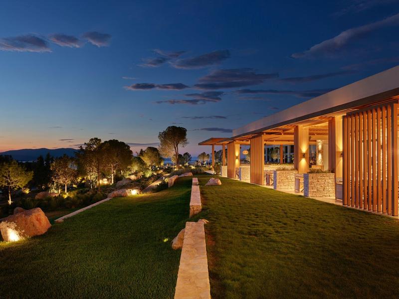 Nowoczesny hotel z oświetlonym tarasem i zadbanym trawnikiem o zachodzie słońca