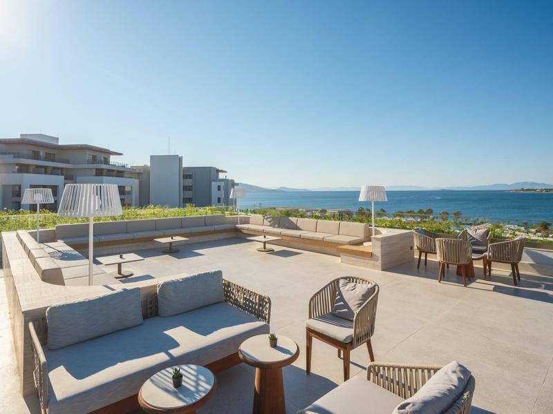 Nowoczesny taras na zewnątrz z miejscami do siedzenia i widokiem na morze pod bezchmurnym niebem.