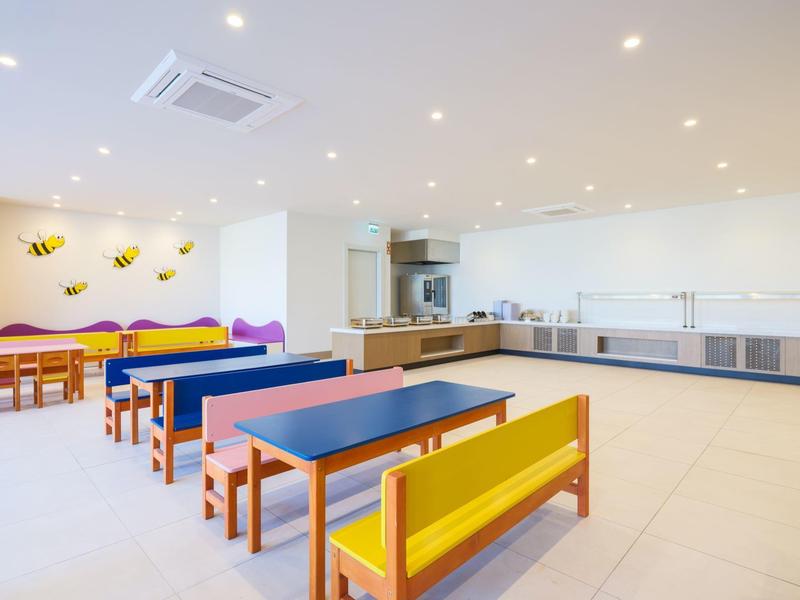 Jasna, nowoczesna kuchnia z kolorowymi ławkami i stolikami w przestronnym pomieszczeniu.