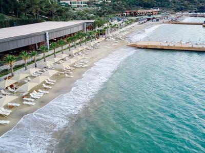 Plaża z leżakami obok długiego molo i spokojnego, turkusowego morza.