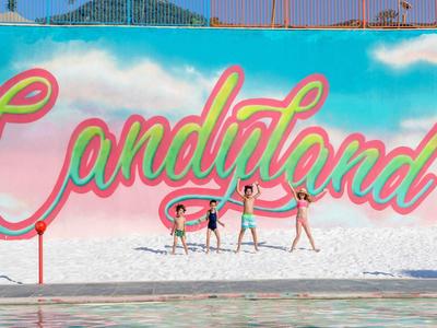 Cztery kobiety spacerują przed kolorową ścianą Candyland na zewnątrz.