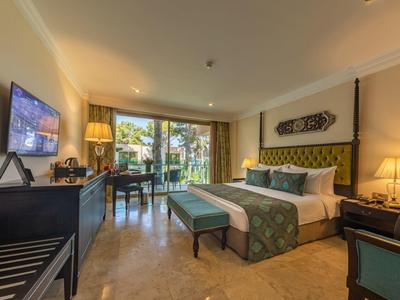 Jasny pokój hotelowy z dużym łóżkiem, biurkiem i wyjściem na taras.