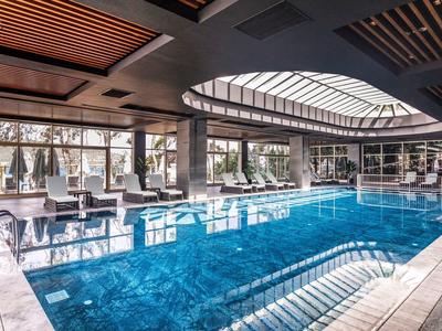 Nowoczesny basen kryty ze szklanym dachem i leżakami w hotelu.