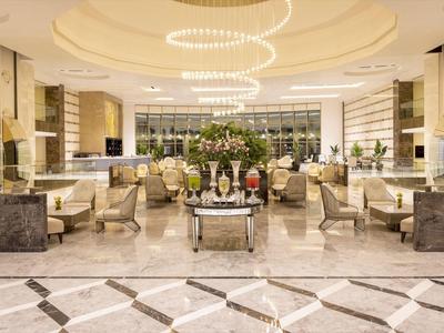 Jasna lobby hotelowa z nowoczesnym oświetleniem i eleganckimi miejscami do siedzenia z beżowymi meblami.