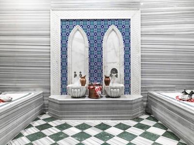 Luksusowy hammam z marmurowymi basenami i niebiesko-białą płytką ścianą.