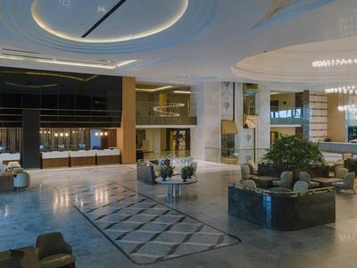 Große Hotel-Lobby mit modernen Möbeln, hellem Marmorboden und indirekter Deckenbeleuchtung.