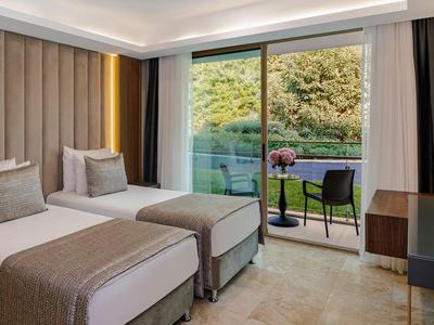 Hotelzimmer mit zwei Einzelbetten und Terrasse mit Blick auf grüne Landschaft