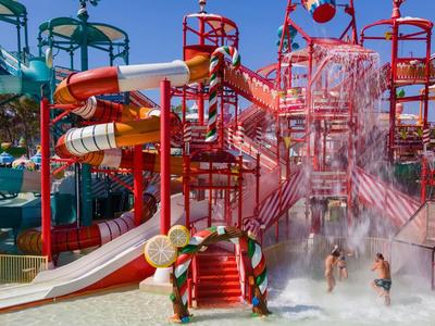 Buntes Wasserpark-Atrium mit Rutschen und Menschen, die in einem großen Planschbecken spielen.