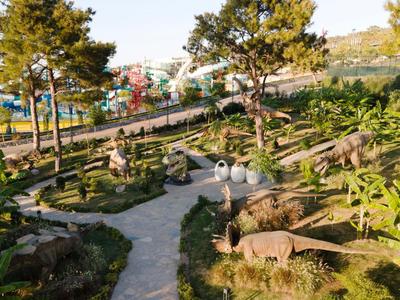 Grüner Park mit Pfaden und Tierfiguren, im Hintergrund Wasserpark-Strukturen.