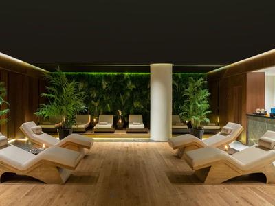 Moderner Hotel-Wellnessbereich mit Holzboden, Liegen und grünen Pflanzen.