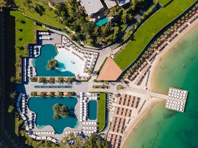 Luftaufnahme eines Strandresorts mit Pools, Liegestühlen und direktem Zugang zum Meer.