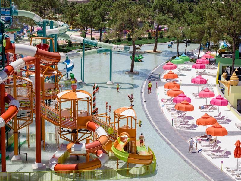 Park wodny z kolorowymi zjeżdżalniami, miejscami do siedzenia i parasolami w ośrodku wakacyjnym.