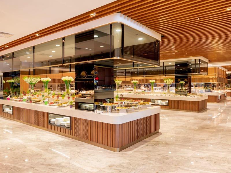 Nowoczesna restauracja bufetowa z przeszklonymi witrynami i różnorodnymi potrawami w eleganckim otoczeniu.