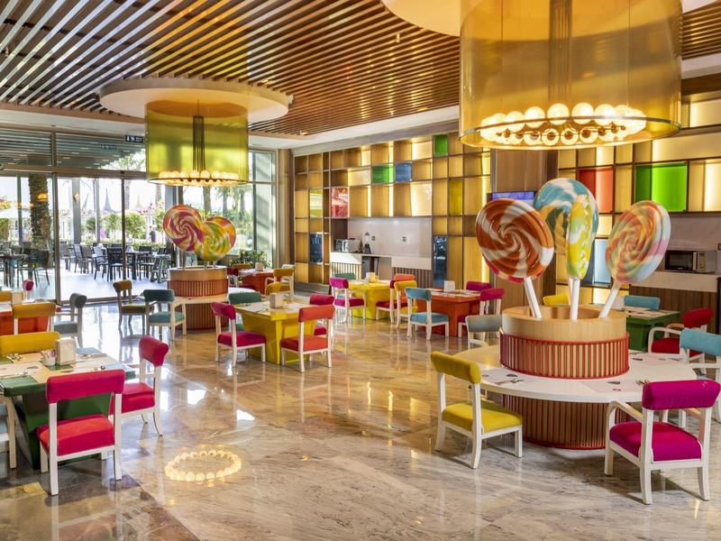 Kolorowa restauracja hotelowa z nowoczesnymi meblami i dużymi oknami.