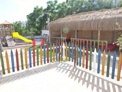 Kolorowy plac zabaw z drewnianym ogrodzeniem i zjeżdżalnią w słonecznym ogrodzie.