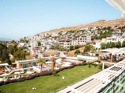 Widok na słoneczne miasto nadmorskie z domami na wzgórzu i zielonym terenem zewnętrznym hotelu.