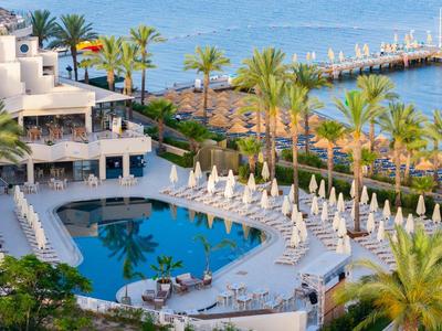 Luxurious hotel pool with lounge chairs and sea view in a tropical setting.