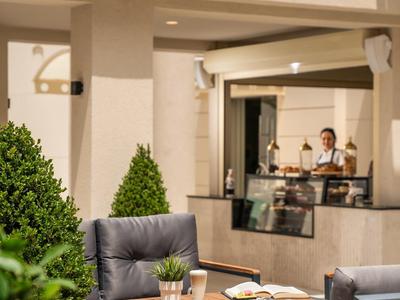Cozy outdoor terrace with padded chairs and a table next to a modern building.