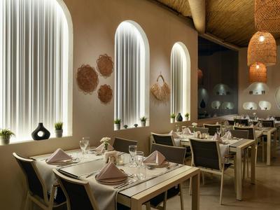 Modern restaurant with bright arches, set tables, and warm natural decor.