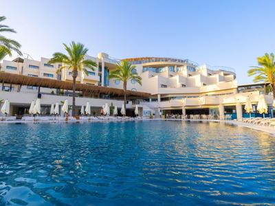 Modern hotel with large pool and palm trees under clear sky