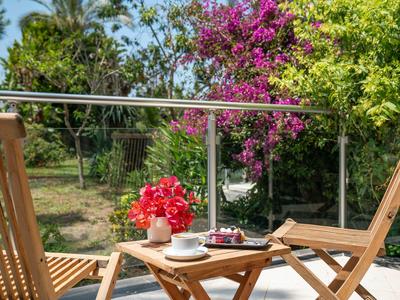 Terrace overlooking garden, two wooden chairs, table with coffee and flowers