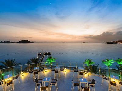 Terrasse eines Hotels mit Sitzgelegenheiten und Blick auf das Meer bei Sonnenuntergang.