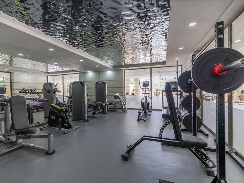 Modern fitness room with dumbbells, weights, and workout equipment in a hotel.
