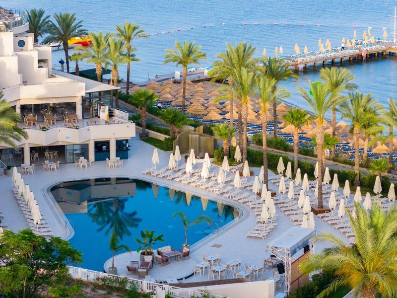 Luxurious hotel pool with lounge chairs and sea view in a tropical setting.