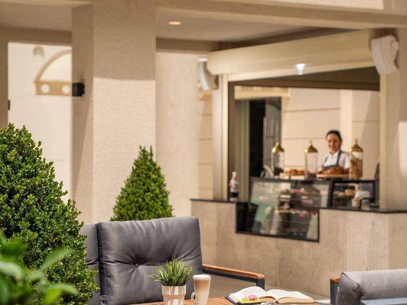 Cozy outdoor terrace with padded chairs and a table next to a modern building.