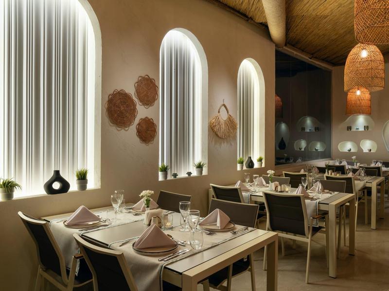 Modern restaurant with bright arches, set tables, and warm natural decor.