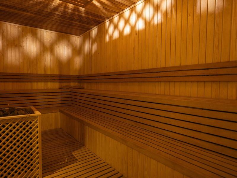 Interior view of a sauna with wooden benches and wall panels under soft lighting.