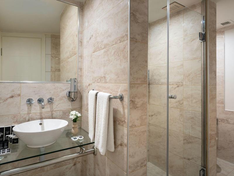 Modern bathroom with glass sink, towels, and glass shower door.